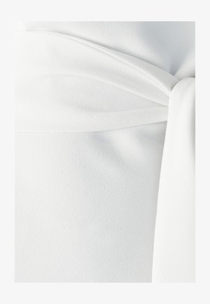 Valkoinen kangas, jossa on pehmeä ja teksturoitu ulkonäkö, sisältäen kietaisu-tyylin ja solmittavan yksityiskohdan vyötäröllä.