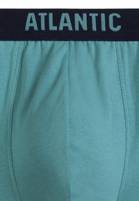 Miękkie, męskie bokserki w kolorze turquoise z granatowym elastycznym pasem, na którym jest wytłoczone "ATLANTIC" w jasnoniebieskim kolorze. Gładki, rozciągliwy materiał o prążkowanej fakturze.
