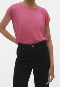 Top rosa a maniche corte con scollatura rotonda, vestibilità rilassata e texture morbida, abbinato a pantaloni neri a vita alta con tasche frontali.