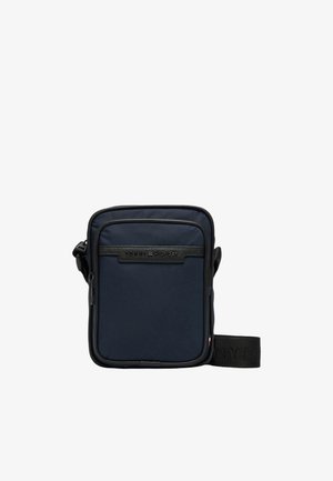 Granatowa torba na ramię wykonana z trwałej tkaniny, z przednią kieszenią na suwak, regulowanym paskiem oraz tłoczonym logo na czarnej wstawce.