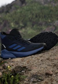 Zapatos de senderismo Terrex con parte superior sintética en negro y azul, suela de goma, dibujo texturizado y acentos azules en los laterales.