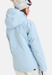 Helle blaue wasserdichte Skijacke mit verstellbarem Kapuze, glatter Textur und weicher Fütterung, ausgestattet mit dezentem Logo am Saum.