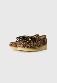 Lepardprint slip-on sko med en teksturert overdel, svarte snørebånd og treperle detaljer. Mykt materiale og en lav, kremfarget såle.