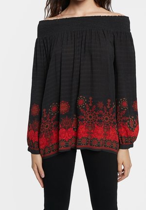 Off-shoulder black blouse with long sleeves and red floral patterns along the hem and cuffs, worn with black pants.