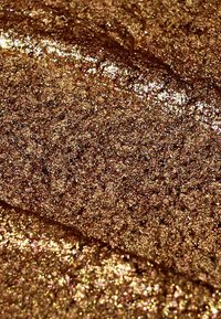 Paillettes dorées métalliques avec des granules fins, exhibant une texture brillante. La surface reflète la lumière, mettant en valeur son éclat vibrant et sa profondeur.
