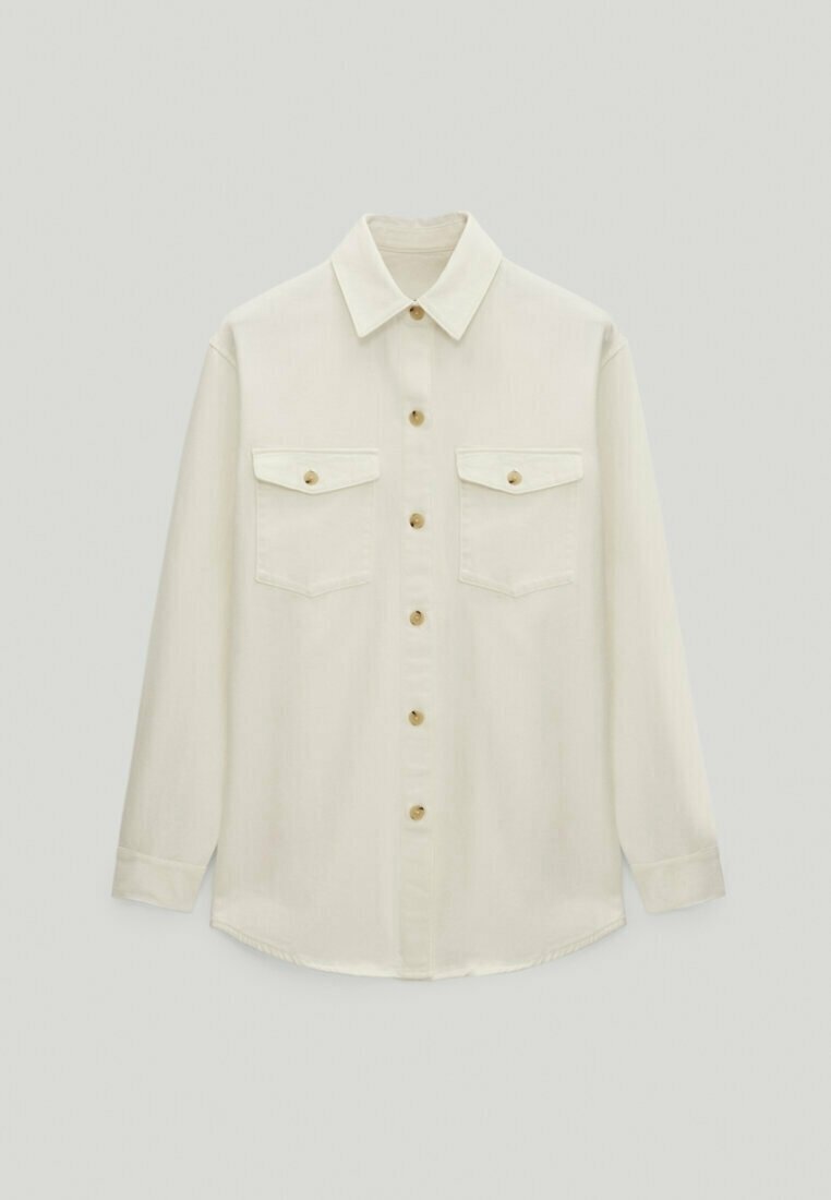 Chemise beige à manches longues avec col pointu et deux poches poitrine à rabats boutonnés.