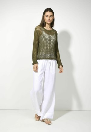 Olive green knitted sweater with open mesh pattern, paired with white linen wide-leg pants featuring two front pockets. Styled with beige sandals.