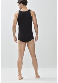 Débardeur en coton noir avec un col arrondi et des bretelles larges. Tissu léger, design ajusté, style minimaliste sans motifs ni accents.