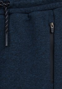 Marinblå joggingbyxor i mjukt tyg, med en strukturerad design, justerbar dragsko och en svart zippered ficka.