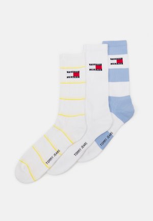 Trois paires de chaussettes en coton de couleur blanche et bleu clair, avec des motifs rayés et des logos "TOMMY JEANS" brodés sur le bord.