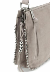 Borsa a mano grigia in suede con accentuazioni di palline metalliche argentate lungo la cucitura. Presenta una chiusura con zip e lacci in tessuto vicino alla cerniera. Design strutturato.