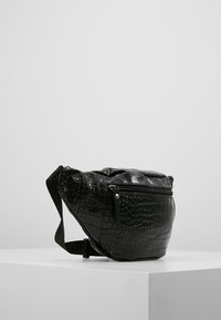 Marsupio in finta pelle nera con texture a coccodrillo, forma curva, tasca frontale con zip e tracolla regolabile.