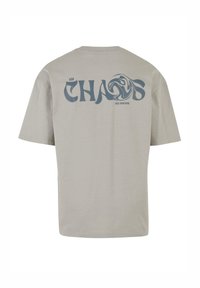 Lys grå bomulds T-shirt med et stort blåt grafisk design med teksten "CHAOS" og "FREE YOUR MIND" på ryggen. Korte ærmer, afslappet pasform.