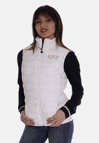 Gilet rembourré blanc avec col haut, fermeture éclair et logo EA7 brodé. Présente des manches noires contrastantes et des détails en accent doré.