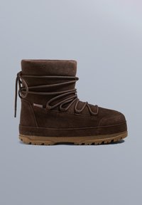 Brązowy zamszowy but za kostkę z grubą, fakturowaną gumową podeszwą, posiadający wiązania na krzyż, wyściełany kołnierz oraz wzmocnione szwy.