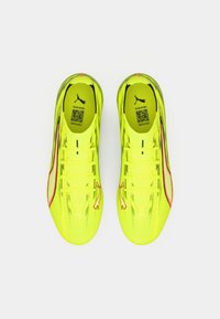 Neoonkollased jalgpallikummikud tekstureeritud pinnaga, roosade detailide ja Puma logoga. Disainitud soorituseks, paelaga kinnitatavad.