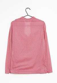 Langarmhemd in Pink mit einem geometrischen Zickzackmuster, aus leichtem Stoff, an einem schwarzen Haken vor einem weißen Hintergrund aufgehängt.