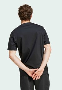 Svart kortärmad t-shirt i mjukt tyg, med rund halsringning och avslappnad passform. Baksidan visar en slät textur och rena linjer.