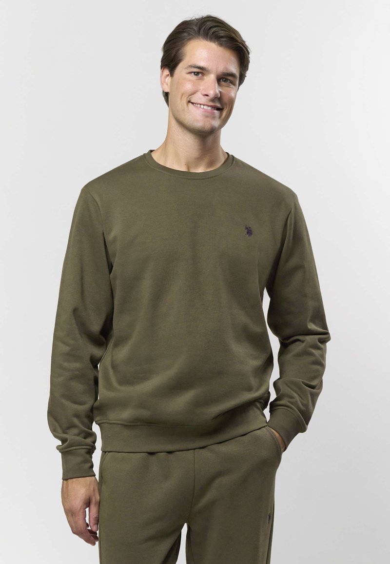 Olivengrønn genser med lange ermer, rund hals, myk tekstur, med en liten brodert logo på brystet.