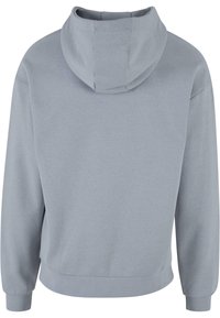 Sudadera gris claro con una textura suave, que presenta un bolsillo canguro y puños acanalados, diseñada con un corte relajado y un cuello alto.