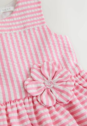 Vaaleanpunavalkoraidallinen mekko, jossa kukkakoriste päälliosassa, valmistettu pehmeästä materiaalista ja liehulahkeisella hameosalla.