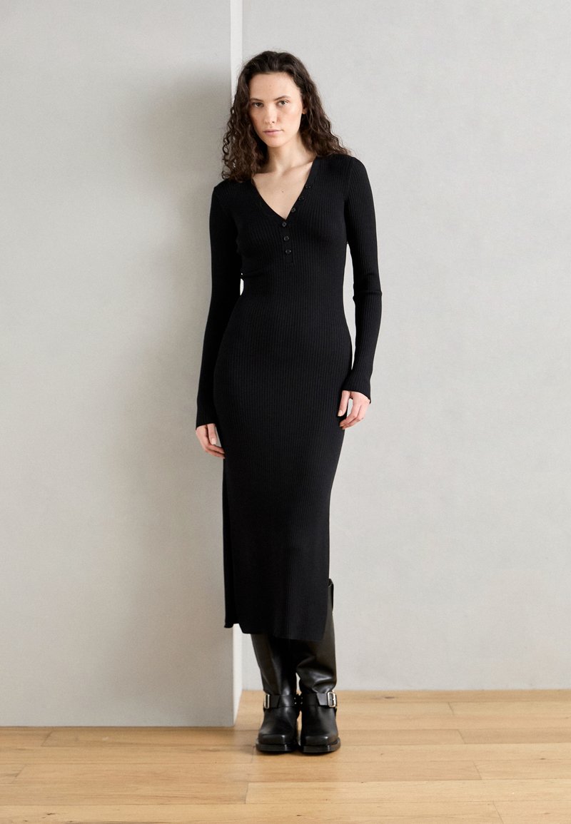 Black ribbed knit dress featuring a V-neck and long sleeves, with a fitted silhouette and three-button detail at the neckline.