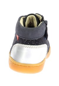 Botín de ante negro con tacón de cuero plateado, suela de goma y cremallera lateral. Los acentos de purpurina en la parte superior crean textura e interés visual.