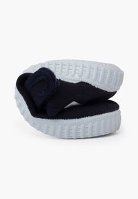 Zapato de tela suave en color azul marino con suela de goma blanca. Presenta una punta redondeada y un diseño flexible. Ligero y compacto.