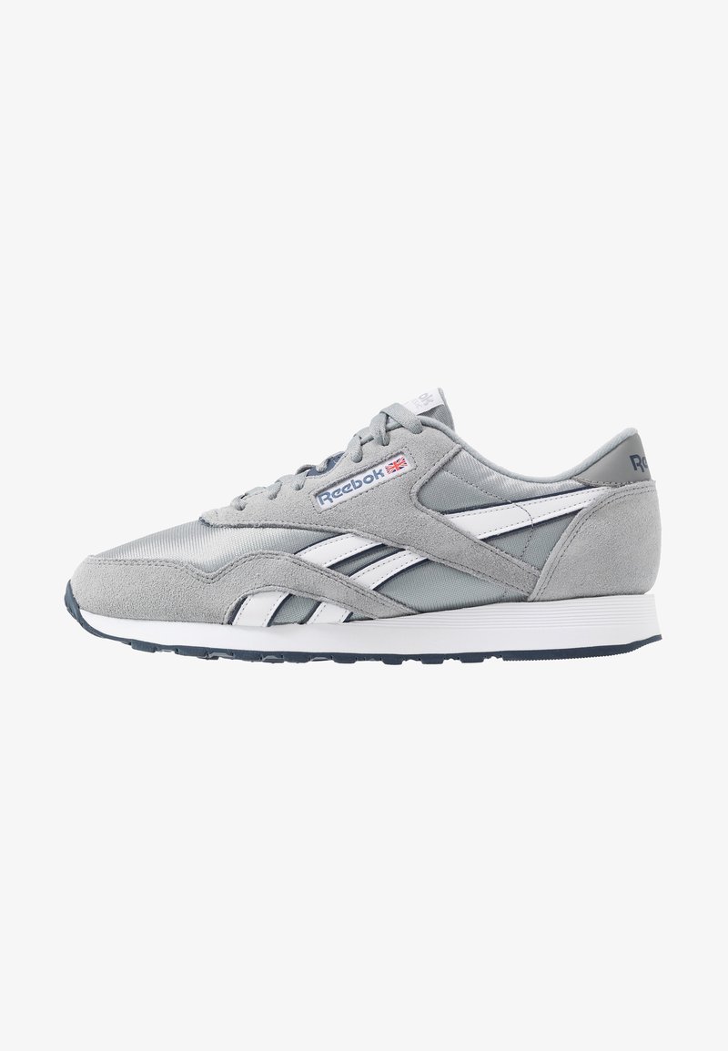 Baskets Reebok grises et blanches en suède et mesh, avec des lacets et un petit drapeau Union Jack sur le panneau latéral du logo.