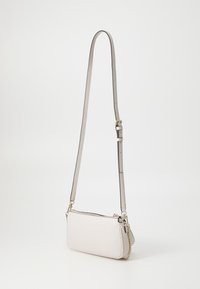 Crossbody-Tasche aus hellbeigem synthetischem Material, rechteckige Form, mit einem langen verstellbaren Tragegurt, Kettenakzent und Reißverschluss.