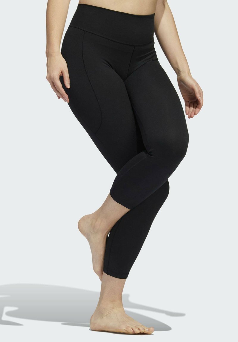 Leggings noirs avec une taille haute, fabriqués en matériau extensible. Présentent un design ajusté et une coupe jusqu'aux chevilles. Texture lisse, sans motifs.