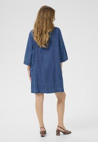 Denim jurk met driekwartmouwen, een losse pasvorm en een ruwe zoom. Gecombineerd met blokhak sandalen met leopardprint.