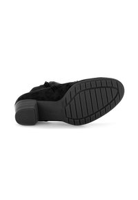 Bottine noire en daim avec un talon carré et une semelle en caoutchouc texturé. Dotée d'une fermeture éclair et d'un branding minimal sur le talon.