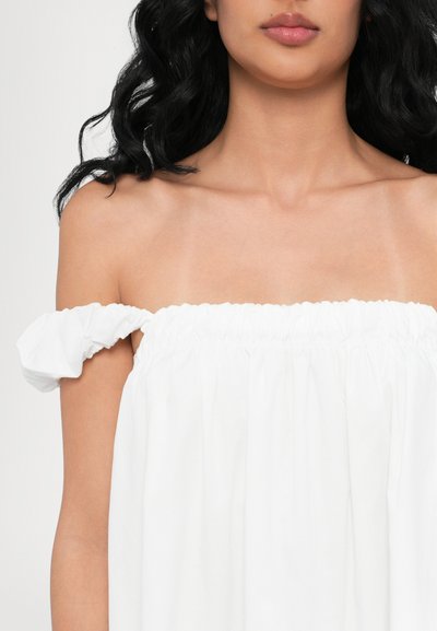 Rochie albă cu umerii goi, cu guler elastic plisat și bretele cu puff. Țesătură fină cu un croi lejer și fluid.