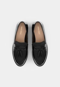 Svarta loafers med lackläderfinish, med platt design, kvastdekorationer och en slät textur. Logotyp synlig på innersulorna.