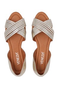 Strappy slidesandalen met metallic zilveren kruissluipschoenen en een tan leren voetbed, met een gladde textuur en open hielontwerp.