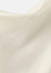 Tela color marfil claro con una textura suave y lustrosa que presenta un brillo sutil y un caída delicada, mostrando una apariencia suave y fluida.