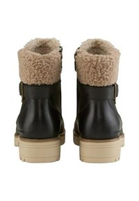 Czarne skórzane buty z beżowymi, puszystymi mankietami ze shearlingu, z masywną jasnozłotą podeszwą i bocznym zapięciem w formie klamry.