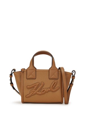 Small textured brown leather handbag with top handles, adjustable shoulder strap, and stitched name detail on front panel.