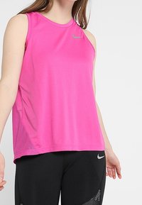 Růžové atletické tílko z lehkého materiálu s kulatým výstřihem a síťovanými bočními panely. Na prsou má malé šedé logo.