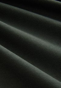 Teksturowana ciemnozielona tkanina z widocznymi równoległymi fałdami, ukazująca wzór tkania oraz trwałą, lekko szorstką powierzchnię.