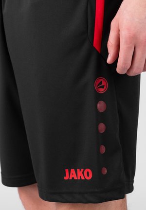 Zwarte sportshorts met rode accenten. Heeft een cirkelvormig logo en gestippelde details aan de zijkant. Gemaakt van een gladde, lichte stof.