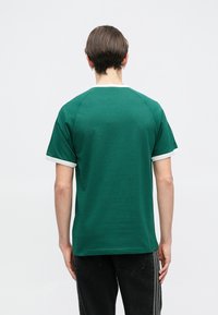 Πράσινη κοντομάνικη μπλούζα με λευκό γιακά και τελειώματα στα μανίκια, με λεία υφή και χαλαρή γραμμή.