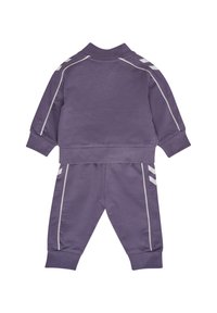 Lila träningsdräkt i mjukt tyg, med en zip-up jacka med vita ränder på ärmarna och matchande byxor med randiga detaljer.