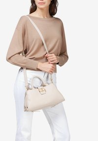 Beige lædertaske med en struktureret form, top-håndtag og en aftagelig skulderrem. Har guldtonet hardware og en klaplukning.