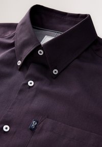 Dunkellila Hemd mit Knopfleiste, einem Kragen, weißen Knöpfen, einer Brusttasche und einem kleinen Logoetikett auf der Tasche. Glatte Textur.