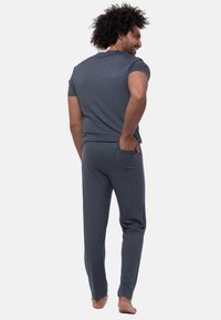 Grijze loungewear set met een t-shirt met korte mouwen en broek met elastische taille en zakken. Zachte textuur, losse pasvorm en minimalistisch ontwerp.