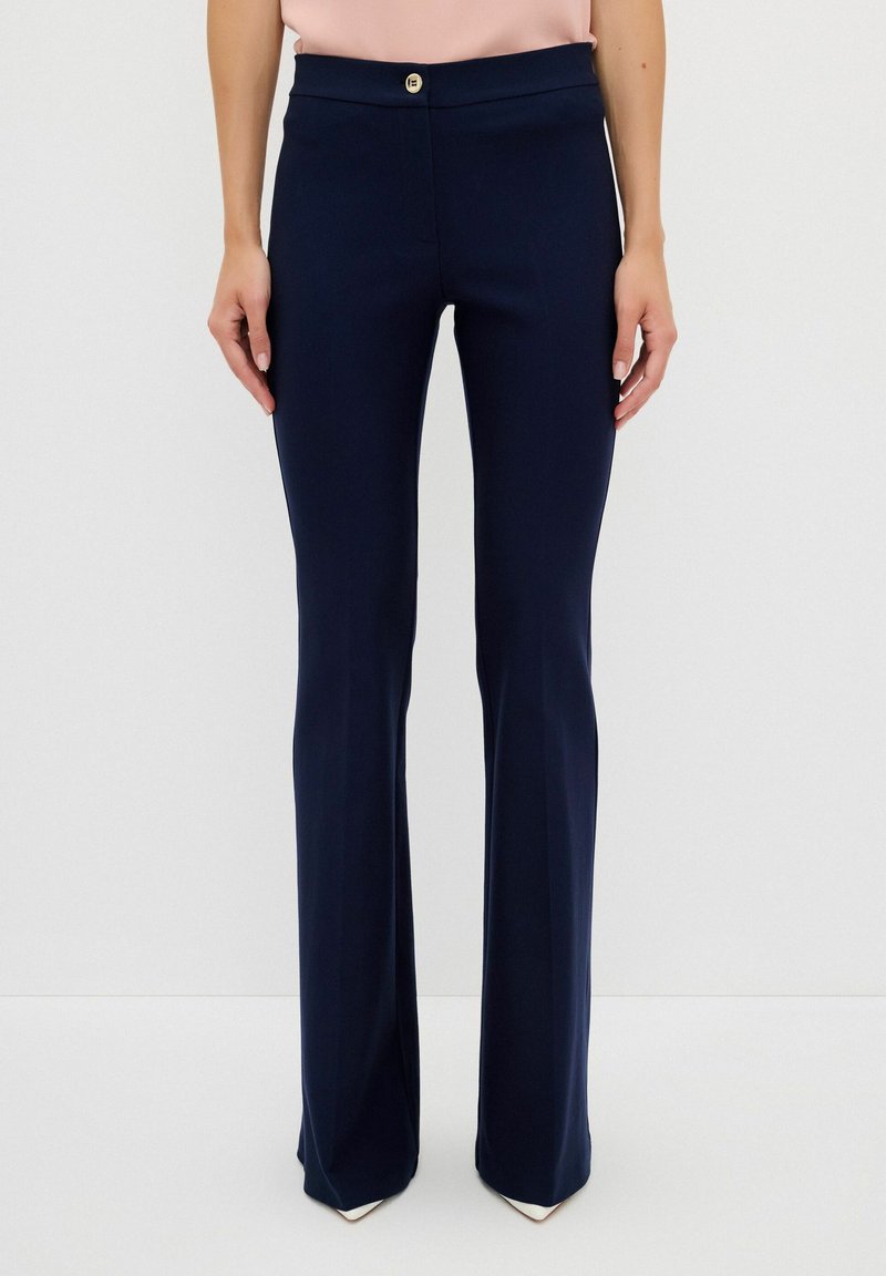 Marina byxflair i en slät tygkvalitet med en platt midja och detaljer i guldknapp. Strukturerad passform med en lätt stretch.