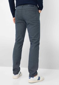 Grijze getextureerde broek met een slim fit, voorzien van een tailleband en achterzakken, gecombineerd met witte en blauwe sneakers.