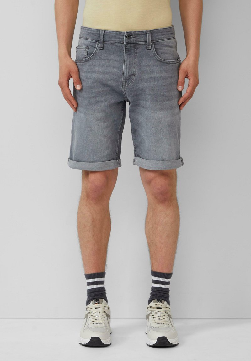 Grau Denim-Shorts mit umgeschlagenen Säumen, fünf Taschen und Knopfverschluss. Kombiniert mit grau-weißen gestreiften Socken und beigen Sneakers.